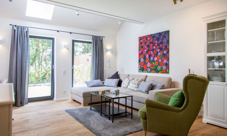 Helles Wohnzimmer der ebenerdigen Ferienwohnung Eger mit Sofa, Ohrensessel und Terrassentür